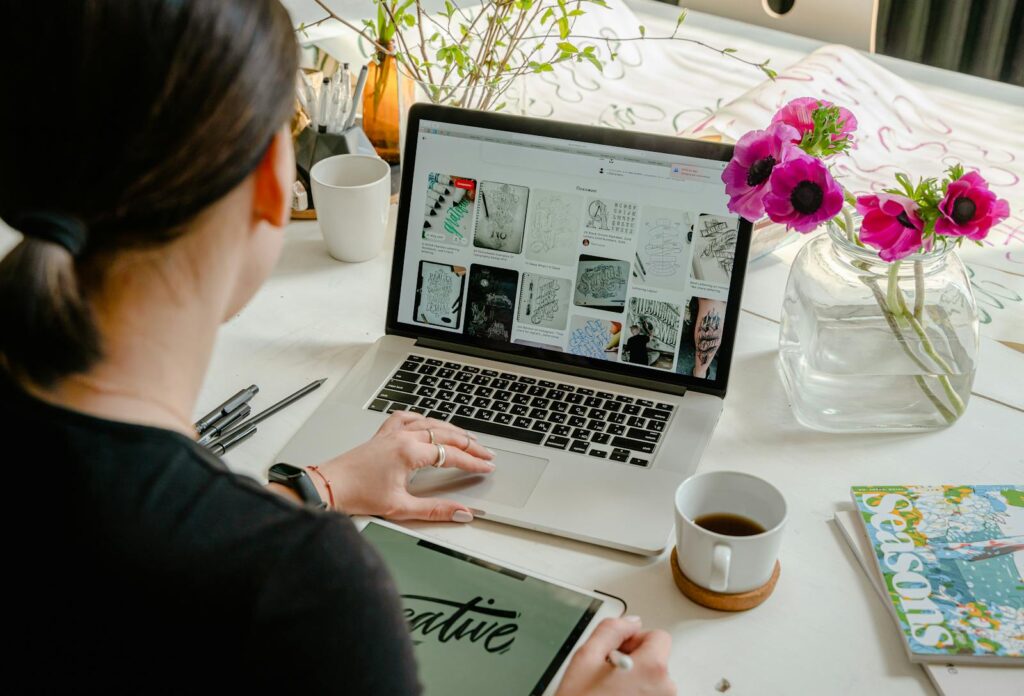 Woman in a creative workspace using a laptop and tablet for calligraphy. Artistic and tech-driven environment for use in cheapest way to get a website header image
